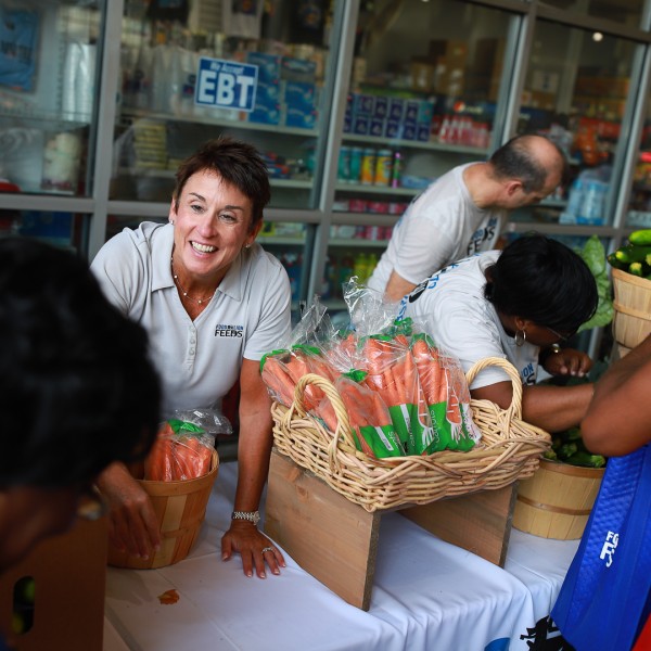 Four people hand out carrots and other produce