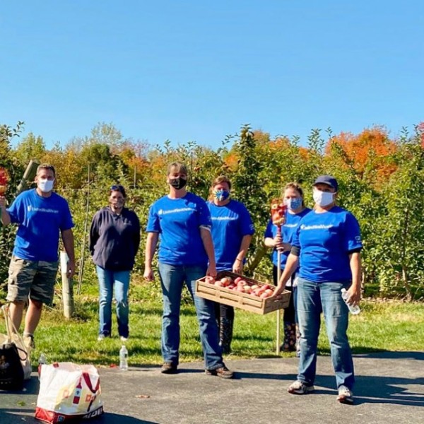 People standing outside at an apple orchard and wearing masks 