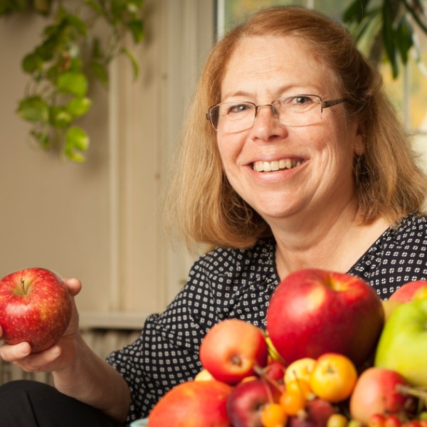 Smiling woman holds apple.