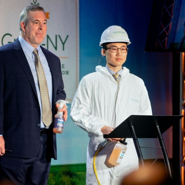 Two men stand on stage at a conference 