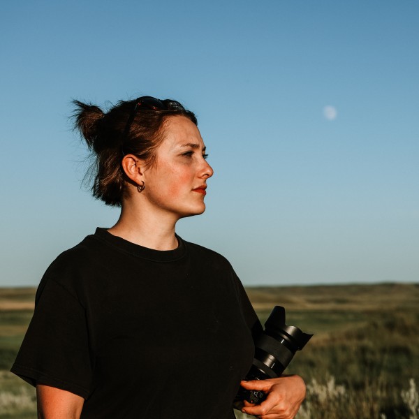 Louise Erskine looks off into the distance holding a camera