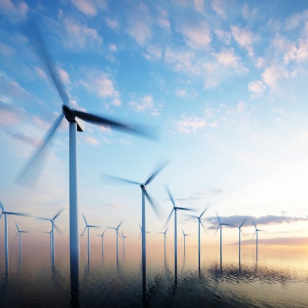 Wind turbines in the middle of the ocean with the sun setting behind them