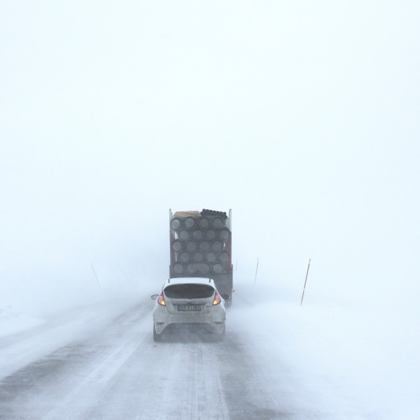 A car and a truck driving along a very snowy road