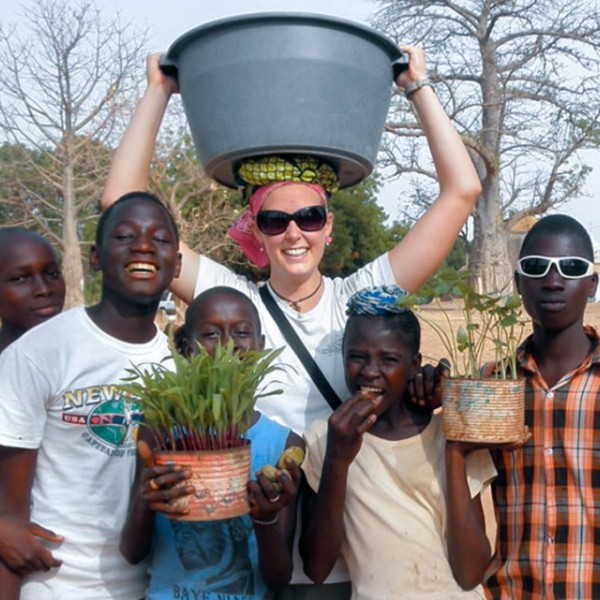 A student standing with five children outside in Africa 