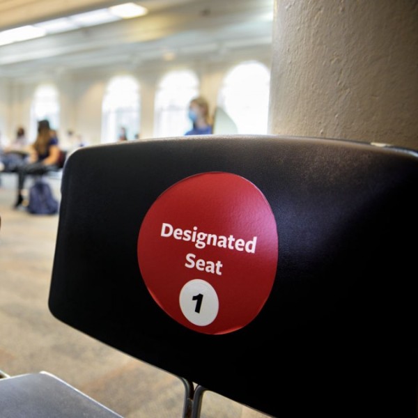 a desk that has a red sticker on it reading "designated seat 1"