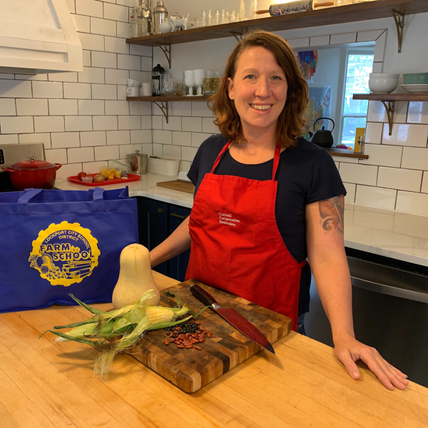 Former Farm to School Educator Mollie McDonough stands next to a counter with a 'Farm to School' meal kit.