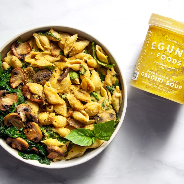 A jar of sauce next to a bowl of pasta.