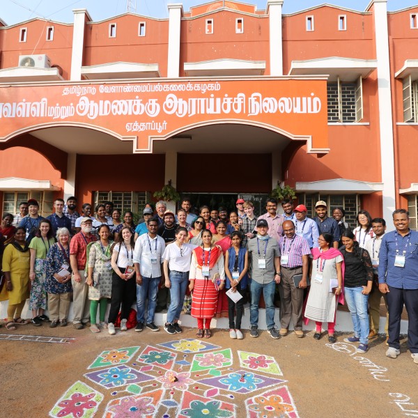 A group of students and professors stand in front of university in India