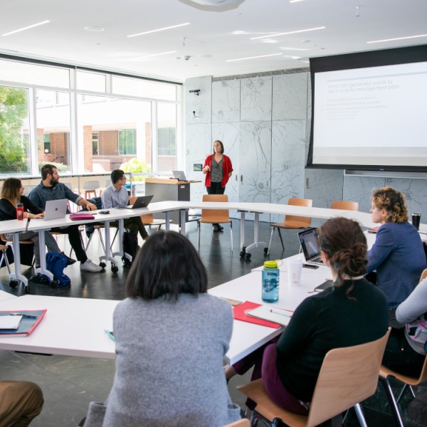 A dozen faculty and staff members sitting in a room at a round table, collaborating