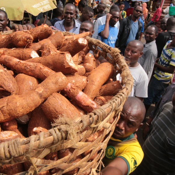 Man carries basket full of cassava in a crowd