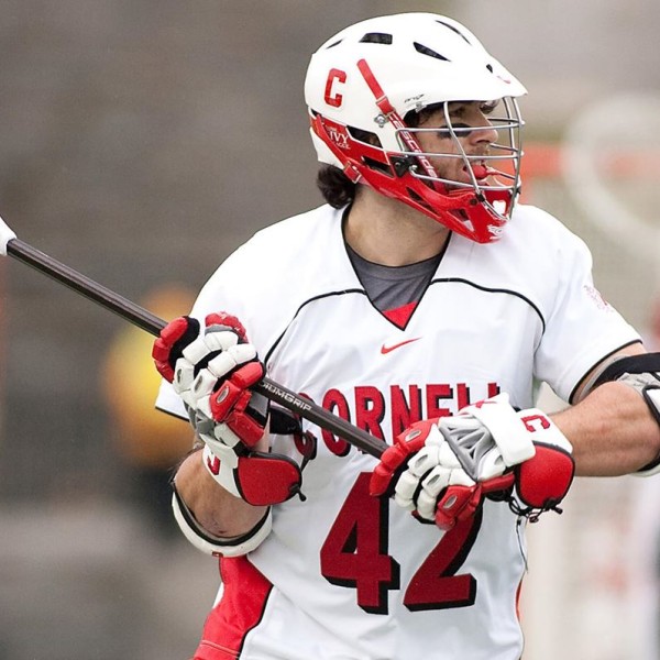 a male lacrosse player raises his stick