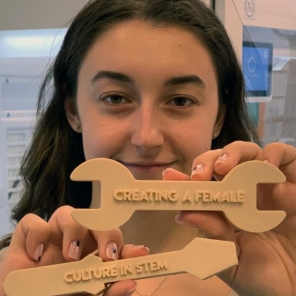 Karina Popovich holding up 3D printed wrenches that say Creating a Female Culture in STEM