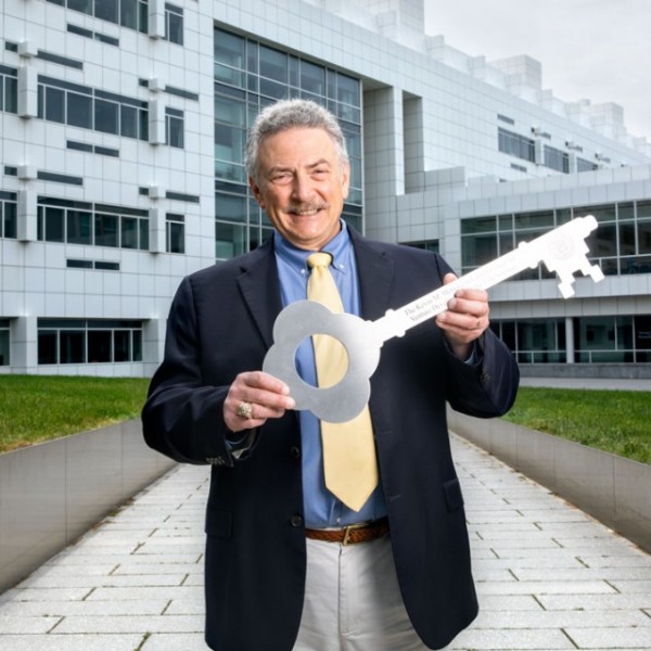 Lou Walcer ‘74 standing in front of Weill Hall holding a large silver key