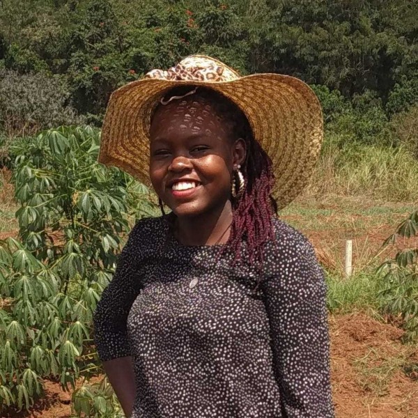 Leah Nandudu stands outside in a cassava field