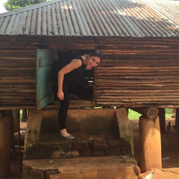 A woman stands in a wooden shack used to store grain