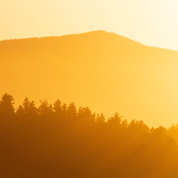 A mountain with sun streaming in behind it