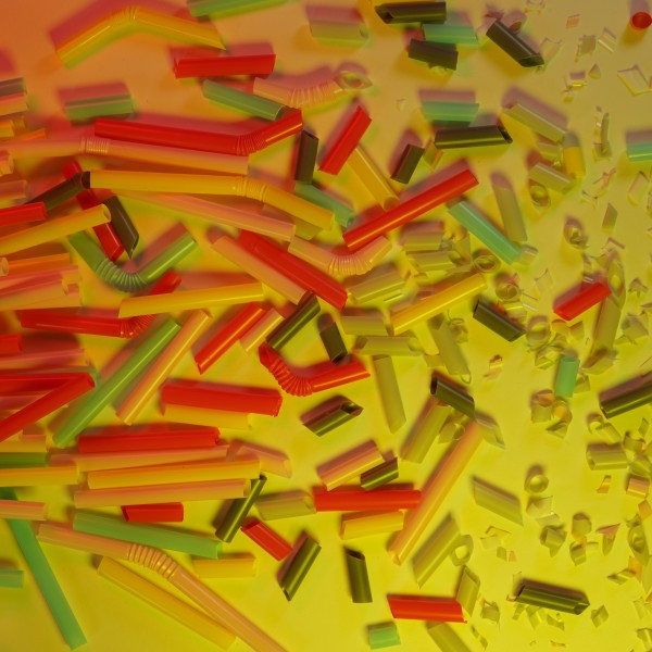 Multicolored straws and small plastic pieces on a yellow table