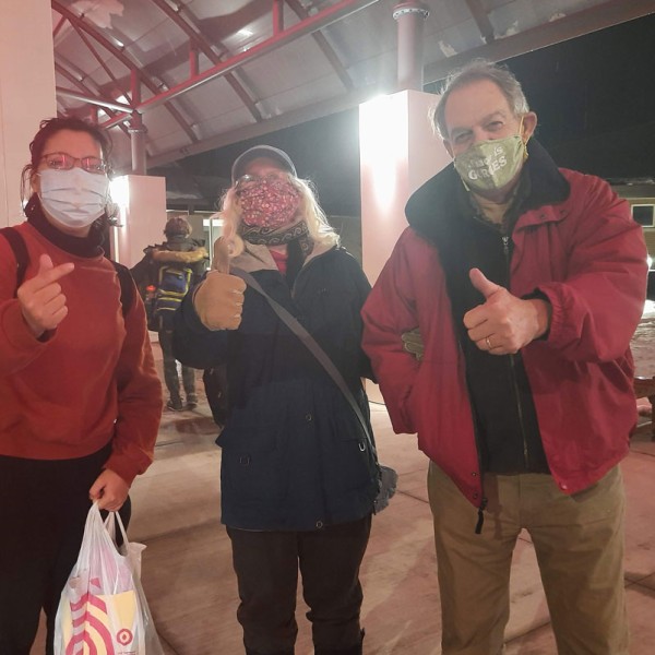 Three individuals show a thumbs up outside