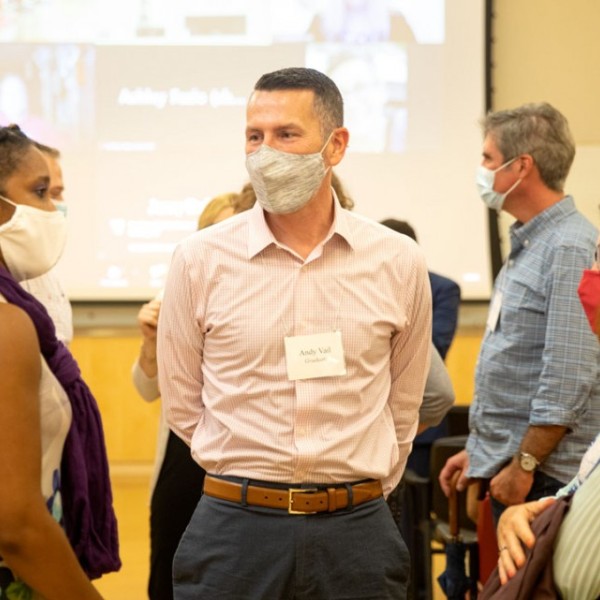 People standing together in a room with masks on talking