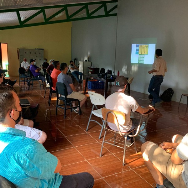 A room with a man presenting in front of a group
