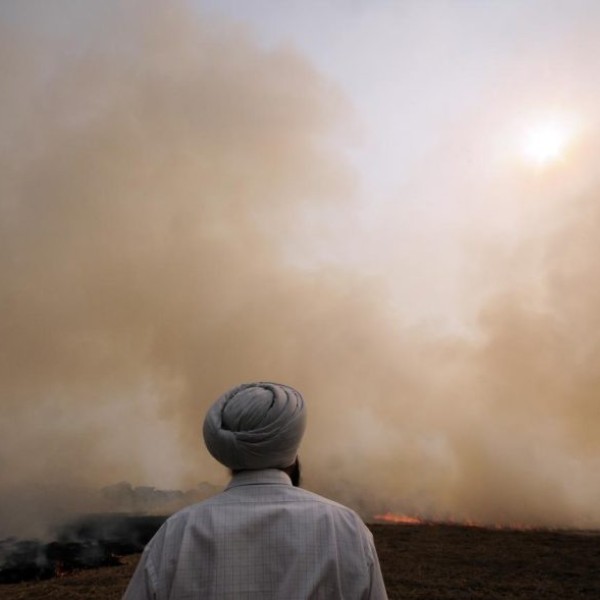 A man stands in front of a smoky landscape