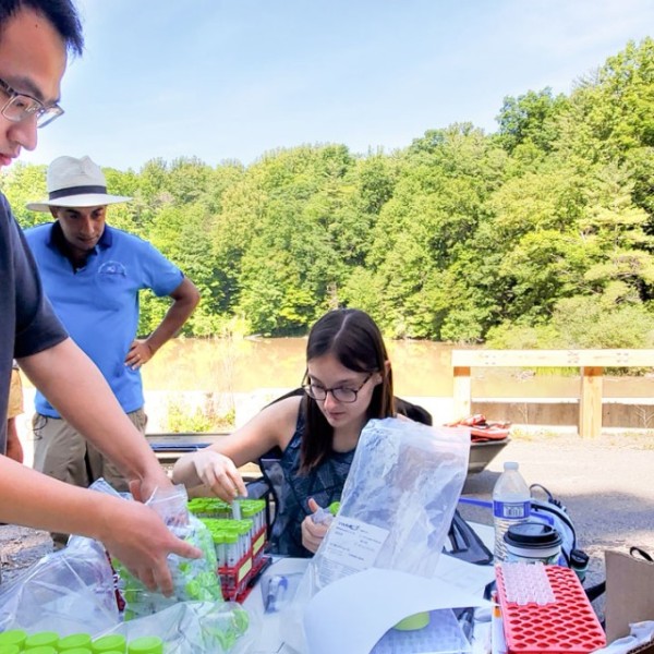 Doctoral student Yi Sang, left, and Olivia Pietz ’22 prepare water samples at the Ithaca City reservoir, as Professor Matt Reid observes the work