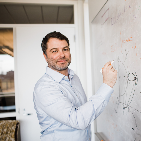 a man in a white shirt draws on a white board