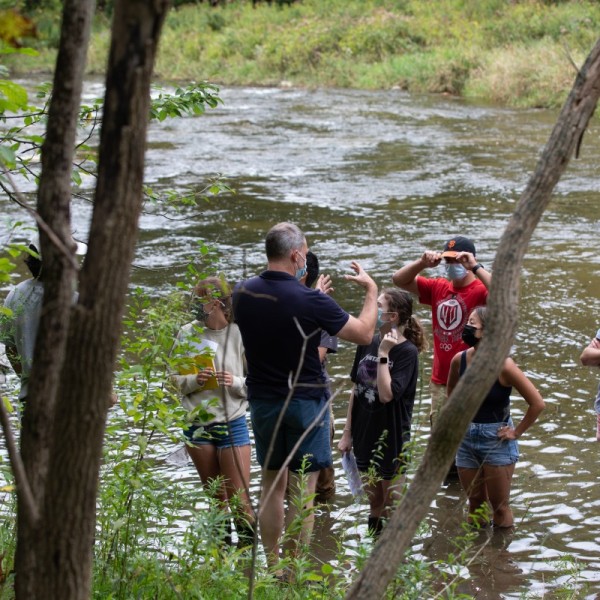 Instructor Marc Goebel and students standing outside in a river while talking
