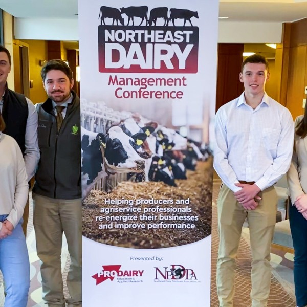 students and faculty pose in front of an event banner