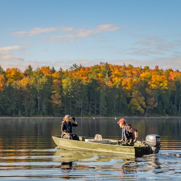 Two people sit in a boat on an Adirondack Lake