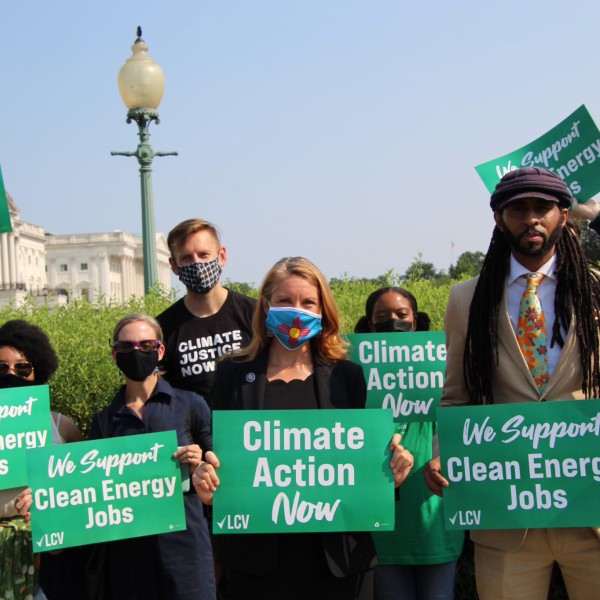 Congresswoman Melanie Stansbury holding a green sign that read "Climate Action Now" with others activists championing climate and environmental policy.