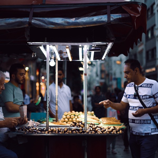Three men stand around street food stand