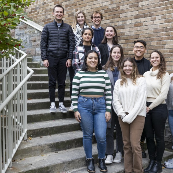 11 Cornell students standing on a staircase smiling at the camera.