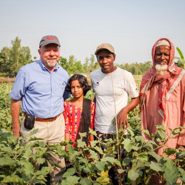 Two older men, a young man, and a girl stand in a field.