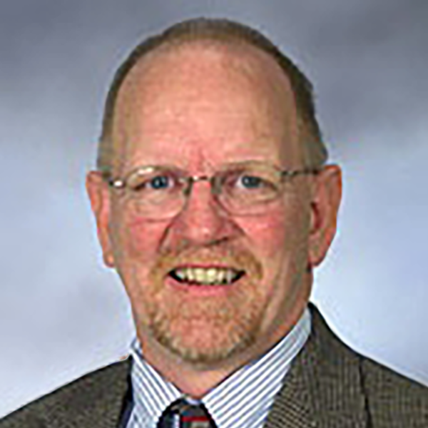 a man in a suit and tie with glasses in front of a blue wall