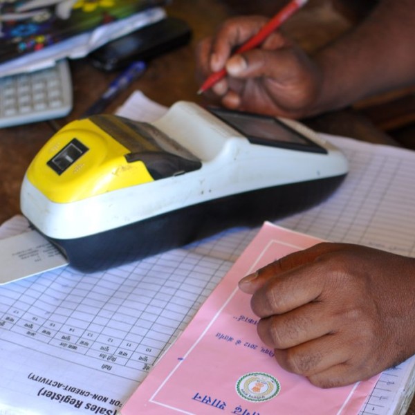 A photo of paperwork on a table, with a calculator, and two hands.