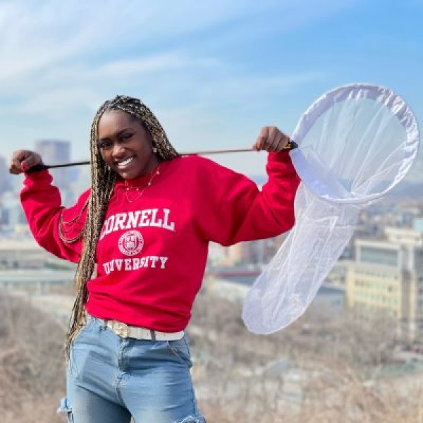 Sylvana Ross poses in a cornell sweatshirt holding a net over her shoulders.
