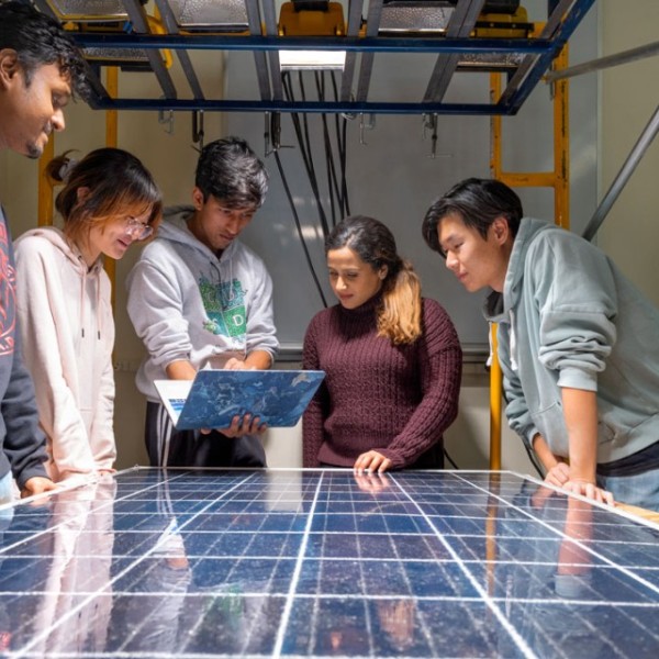 Members of the Solar Panel Reboot team stand around a solar panel