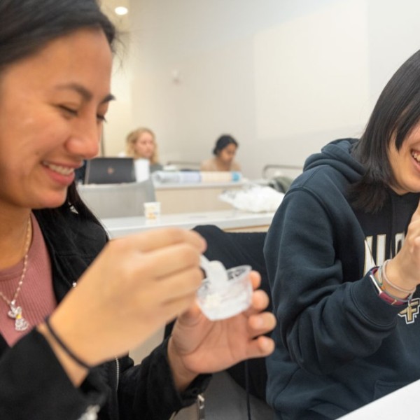 Two female students laughing while eating ice cream.