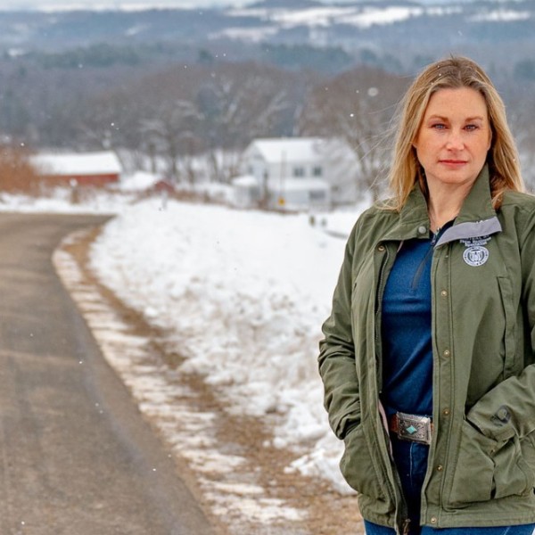 A woman stands by a wintery rural road