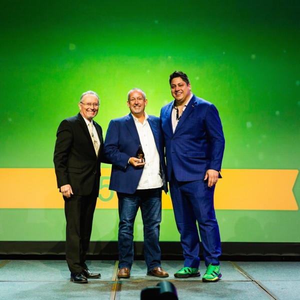 Three men standing in front of a green and yellow background. 