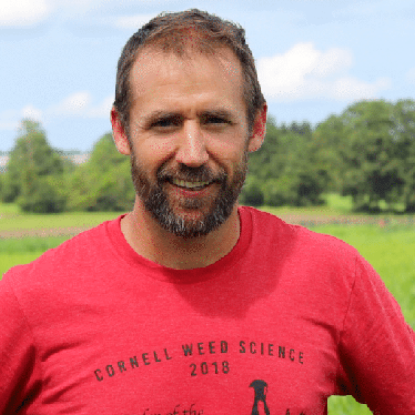 ryan maher in the field wearing cornell weed science tee shirt