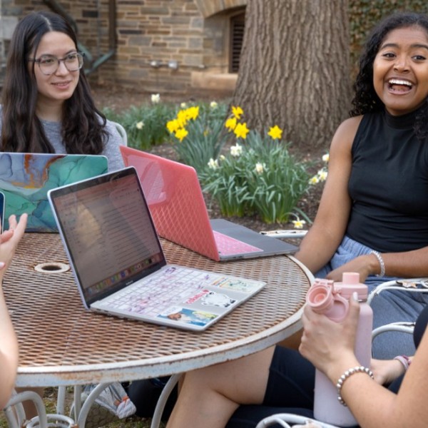 Students sit around a table outside