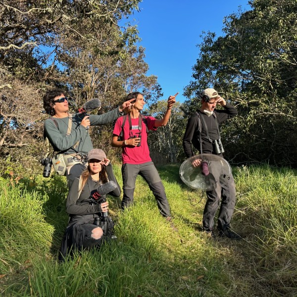 Four students stand outside holding bioaccoustics tools