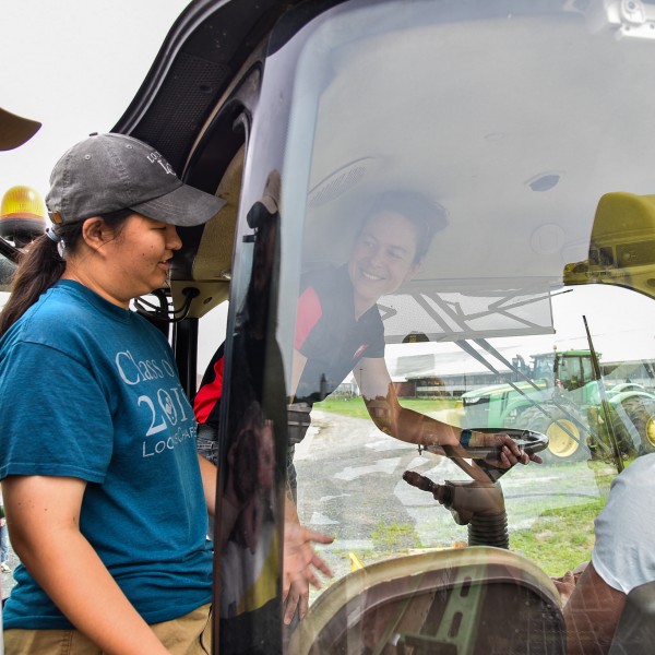 Four people standing near tractor
