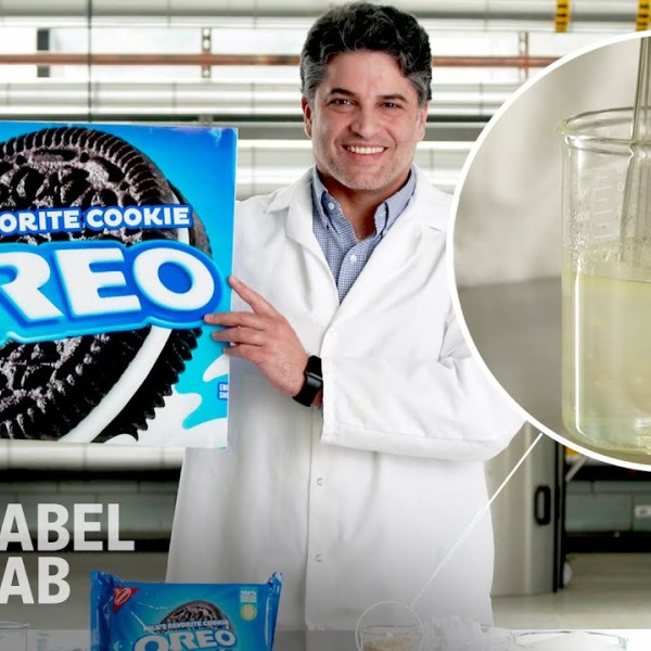 Bruno Xavier wearing a white lab coat holding a sign with the Oreo logo. 