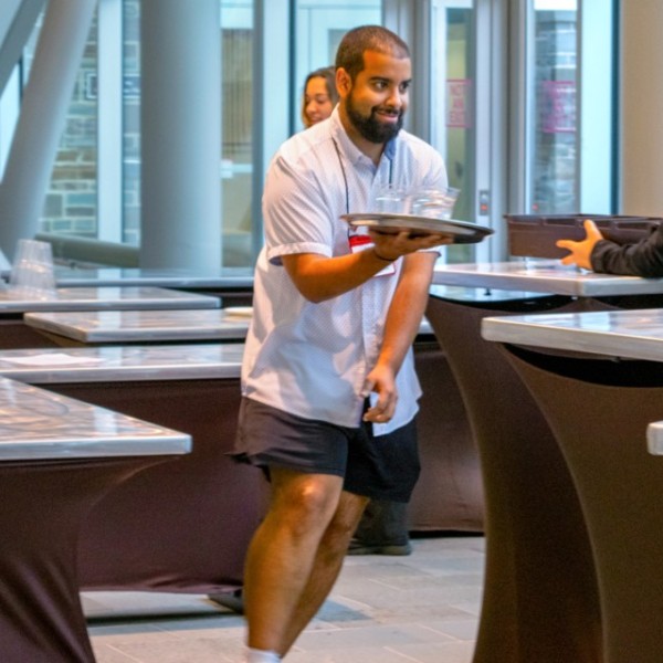 4-H chaperone Juan Carlos Espinal takes part in the waiter and waitress race in Statler Hotel holding a tray with cups on it and weaving around tables. 