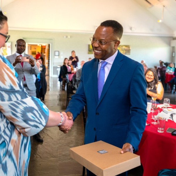 Hubert H. Humphrey Fellow Nodira Kurbanbaeva (left) of Uzbekistan shakes hands with Ed Mabaya in a classroom.