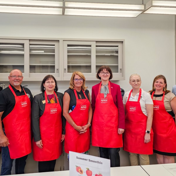 A group of eight people wearing red aprons standing in a row. 