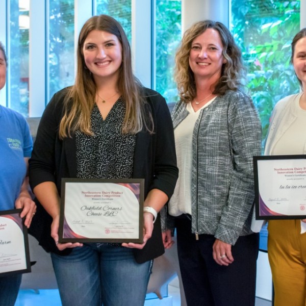 Four women holding award certificates for dairy innovation.